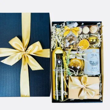 Elegancki złoty box prezentowy z zawartością słodkości, herbaty i cytrynek.